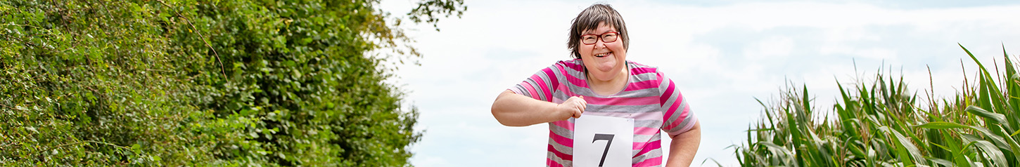 This is a banner photo of a woman with a developmental disability running a race